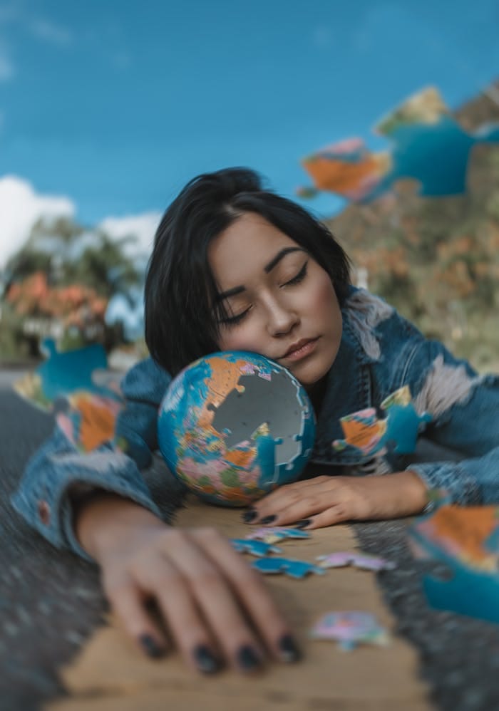 A woman relaxes outdoors with a globe puzzle, capturing a moment of peaceful daydreaming.